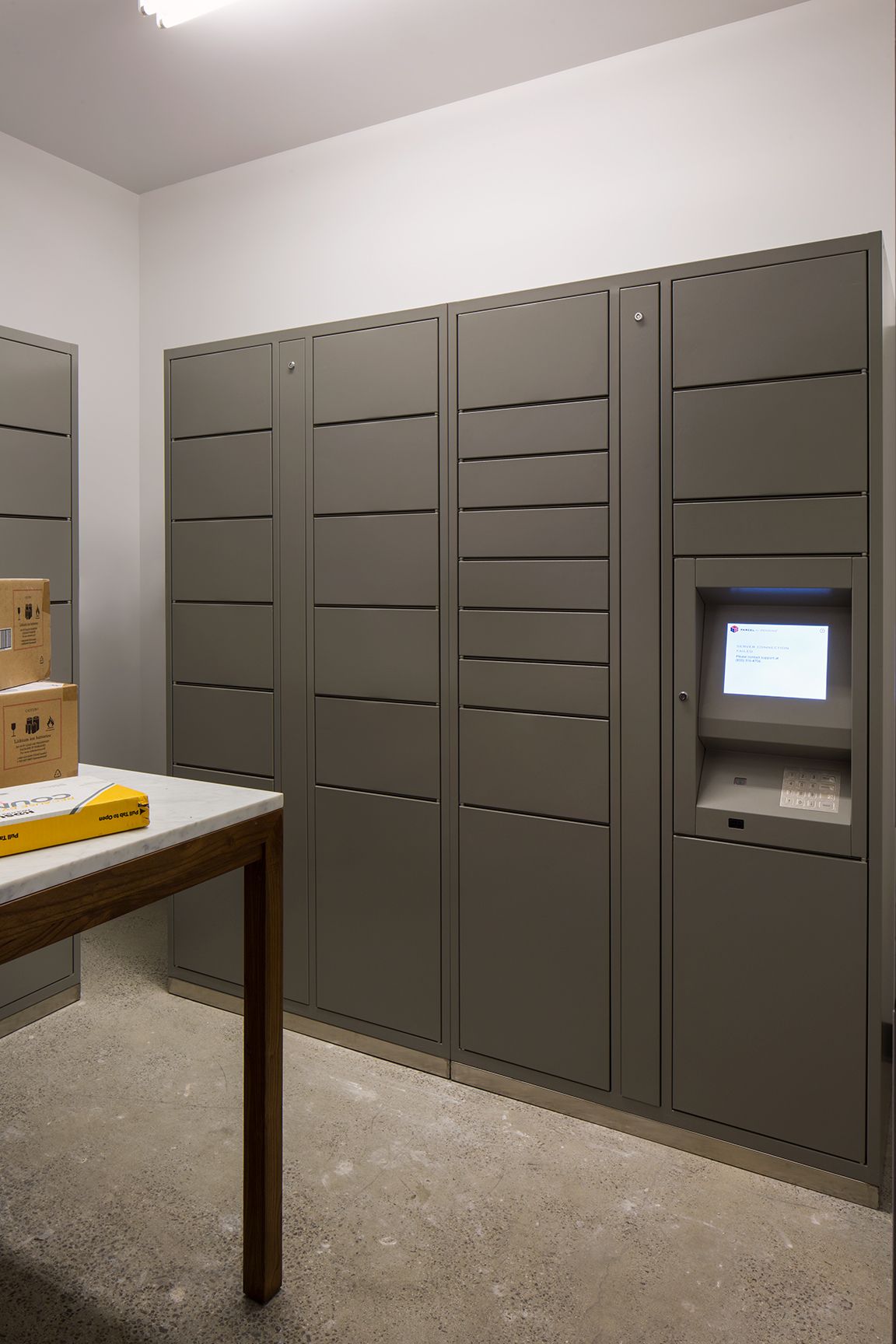 Khu nhận hàng chung cư có tủ locker điện tử và bàn để bưu kiện
